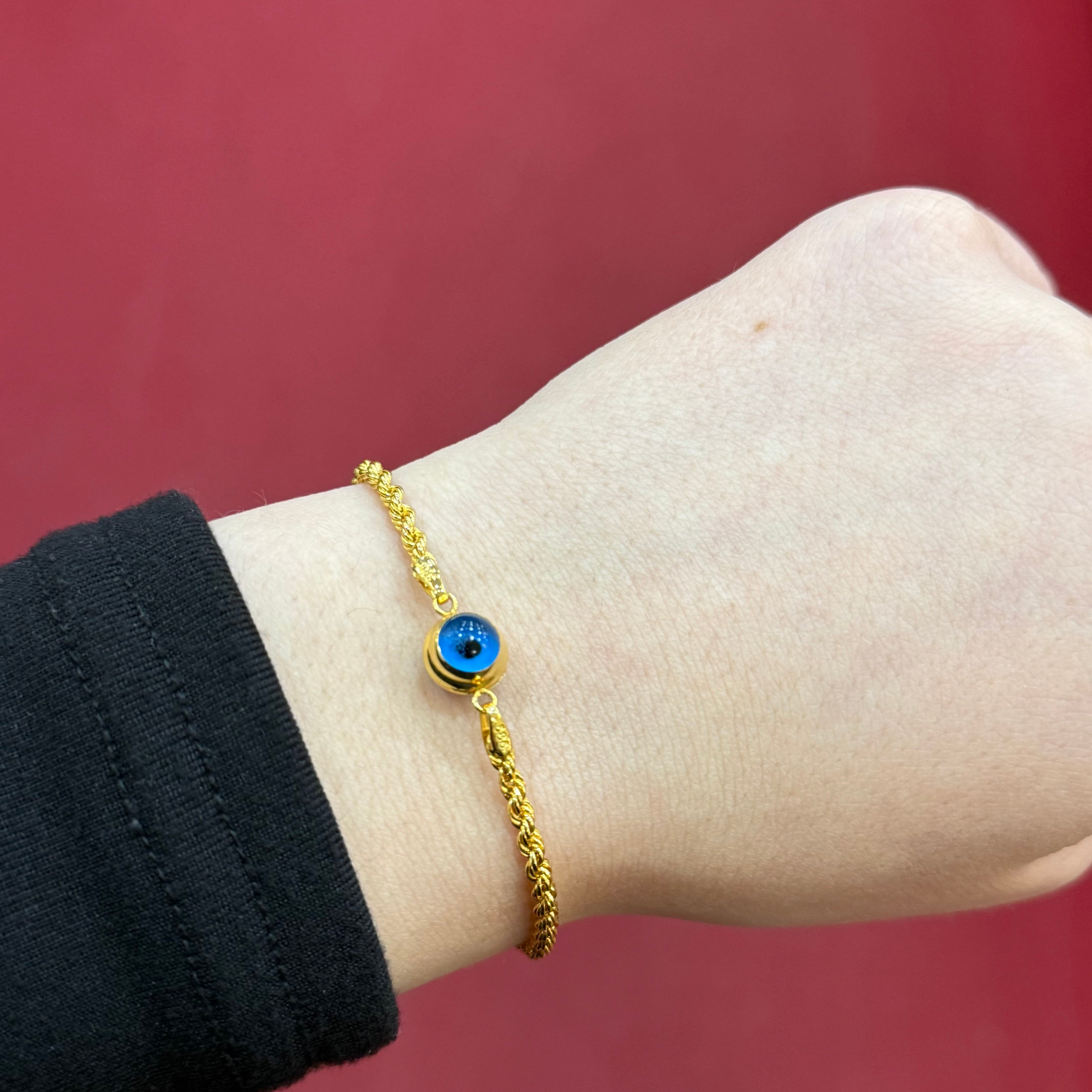 585 Nazarauge Seilarmband aus 14 Karat Gelbgold mit blauem Schutzsymbol am Handgelenk getragen