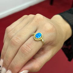 585 Azurya Ring aus Gold 14K mit blauem ovalem Zirkonia und seitlichen Steinen auf Damenhand